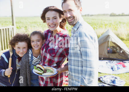 Porträt, Lächeln Familie mit gegrillten Hamburgern auf sonniger Campingplatz Stockfoto