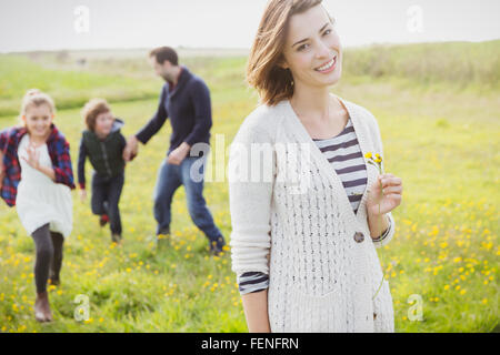 Porträt, lächelnde Frau Holding Wildblumen Wiese mit Familie Stockfoto