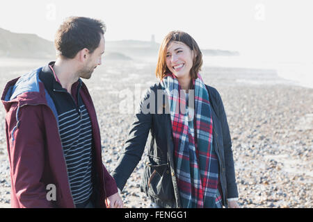 Lächelnde paar zu Fuß am Strand Stockfoto