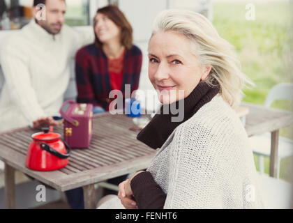 Porträt lächelnd senior Frau am Terrassentisch Stockfoto