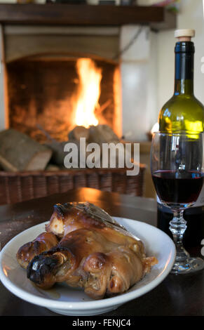 Rotwein Kelch und gebratenes Ferkel rund um den Kamin zu essen Stockfoto