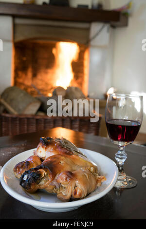 Rotwein Kelch und gebratenes Ferkel rund um den Kamin zu essen Stockfoto