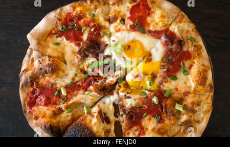 Frühstück Pizza mit Mozzarella, Tomaten, Speck, Wurst und zwei Spiegeleier Stockfoto