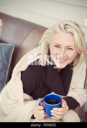 Porträt lächelnd senior Frau trägt Schal Kaffeetrinken auf Terrasse Stockfoto