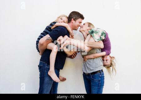 Porträt von Eltern mit zwei kleinen Töchter vor weißer Wand Stockfoto