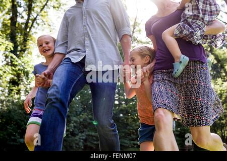 Aufnahme von Eltern und drei Töchter, die im Park laufen beschnitten Stockfoto