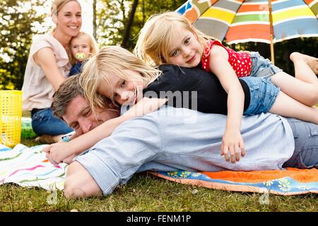 Zwei Töchter liegen oben auf Vater bei Familien-Picknick im park