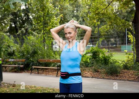 Reife Frau, die Haare zu binden, beim training im park Stockfoto