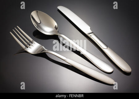 Messer, Löffel und Gabel auf schwarzem Hintergrund Stockfoto