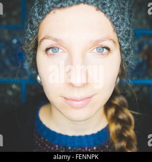Nahaufnahme Portrait junge Frau mit geflochtenem Haar tragen stricken Hut Blick auf die Kamera zu Lächeln
