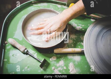 Mitte Erwachsenen mans Hand mitten in der Schüssel mit Wasser auf der Töpferscheibe Stockfoto