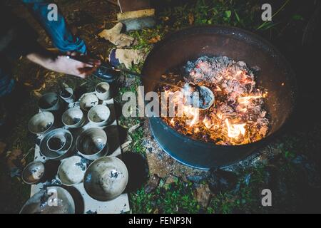 Erhöhte Ansicht der jungen Frau mit Zange Tontöpfe aus Feuer zu entfernen Stockfoto