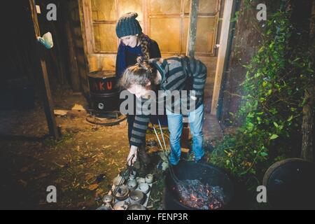 Paar mit Zange entfernen Tontöpfe aus Feuer, Lächeln Stockfoto