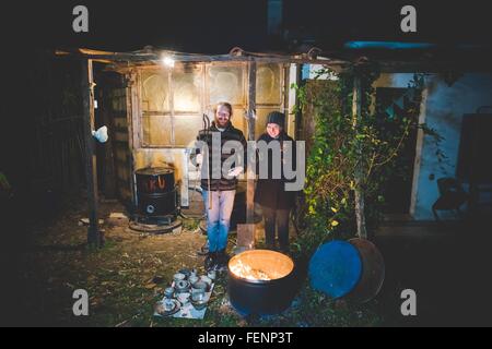 Paar vor Schuppen Holding Zangen, mit Keramik durch einen Brand im Fass Stockfoto