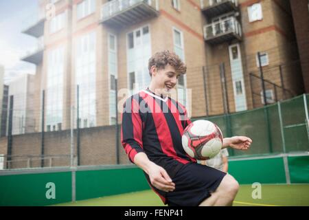 Junger Mann üben fußballerischen Fähigkeiten auf städtischen Fußballfeld Stockfoto