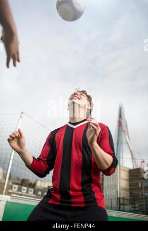 Junger Mann üben fußballerischen Fähigkeiten auf städtischen Fußballfeld Stockfoto