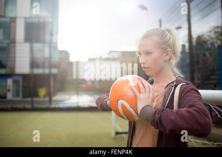 Junge Frau zu werfen Fußball Stockfoto