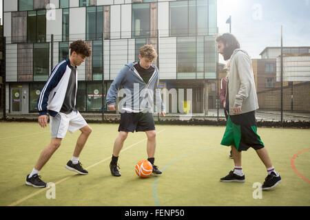 Gruppe von Erwachsenen, die Fußball spielen auf städtischen Fußballfeld Stockfoto