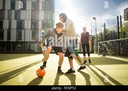 Gruppe von Erwachsenen, die Fußball spielen auf städtischen Fußballfeld Stockfoto