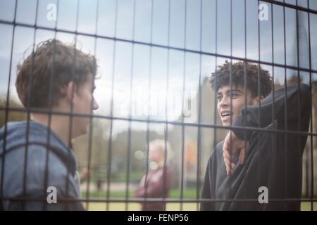 Zwei junge Männer Zaun gelehnt sprechen Stockfoto