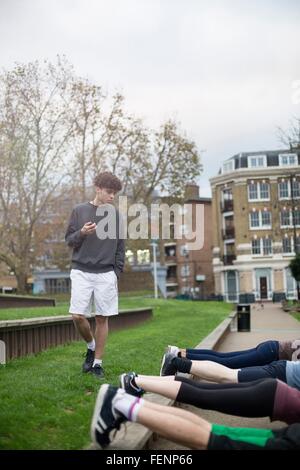 Gruppe von Erwachsenen, die Bewegung in der Natur, jungen Mannes mit Stoppuhr Stockfoto