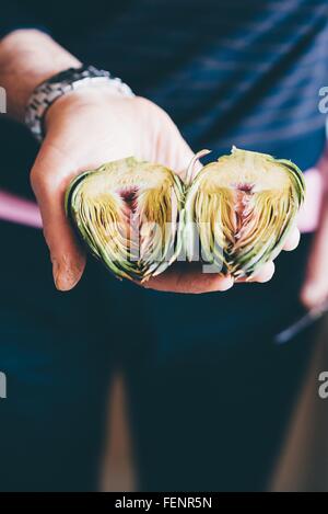 Männliche Hände halten vorbereitet Artischocken Hälften Stockfoto