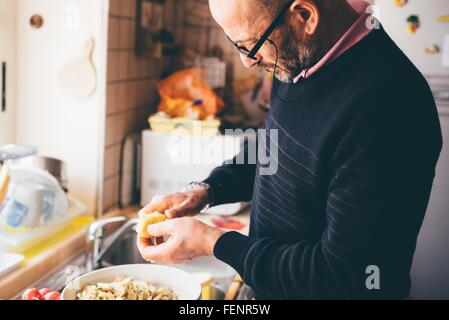 Senior woman schneiden Artischocken in Küche Stockfoto