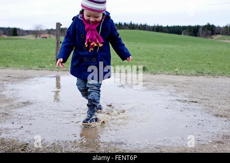 Weiblichen Kleinkind Gummi Stiefel in Pfütze planschen Stockfoto