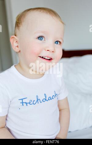 Porträt von niedlichen blauen Augen weiblichen Kleinkind sitzt auf Bett Stockfoto