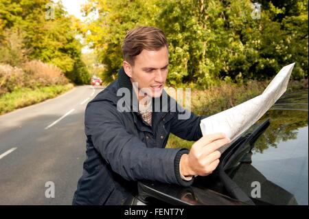 Junger Mann lesen Karte auf Landstraße Stockfoto