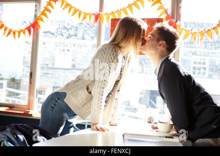 Romantische junge Paar küssen über im Café-Tisch Stockfoto