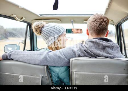 Rückansicht des jungen Paares im Auto am Strand Stockfoto