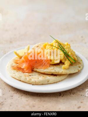 Räucherlachs und Rührei auf Blini mit Schnittlauch garnieren Stockfoto