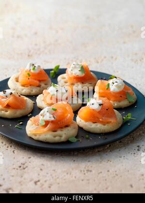 Geräucherter Lachs und Frischkäse auf Blinis mit Schnittlauch und Pfeffer garnieren Stockfoto