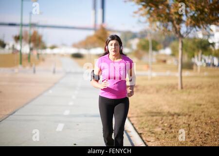 Vorderansicht des Reife Frau trägt Kopfhörer und Armband Joggen am Weg Stockfoto