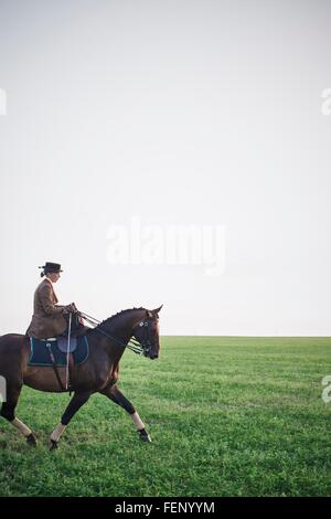 Frau reitet Dressurpferd im Feld Stockfoto