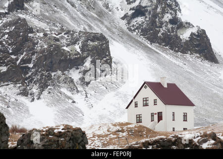 Haus mit Schnee bedeckte Berge bei Arnarstapi, Halbinsel Snaefellsnes, Western Island im Februar in den Schatten gestellt Stockfoto