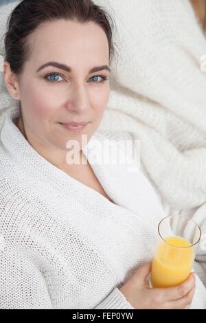 Frau mit Glas Orangensaft zu Hause entspannen Stockfoto