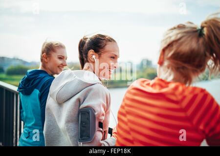 Drei Läuferinnen im Chat auf Stadt-Fußgängerbrücke Stockfoto