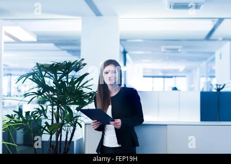 Junge Frau im Büro tragen Telefon Kopfhörer, mit digital-Tablette Blick auf die Kamera zu Lächeln Stockfoto