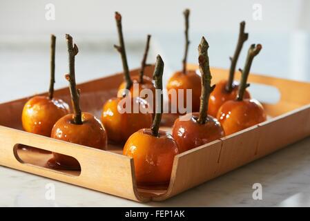 Toffee Äpfel auf Sticks Härten auf Tablett aus Holz Stockfoto