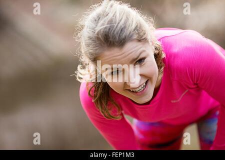 Junge Frau trägt Sportbekleidung bücken erschöpft Stockfoto