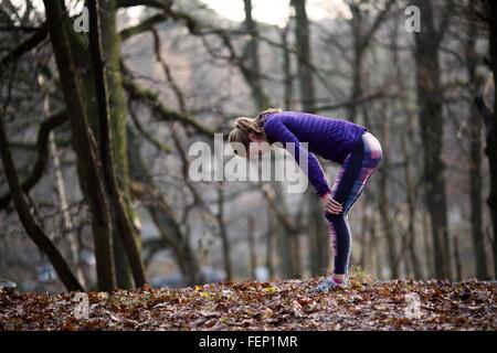 Seitenansicht der junge Frau trägt Sport Kleidung bücken Hände auf die Knie, erschöpft Stockfoto