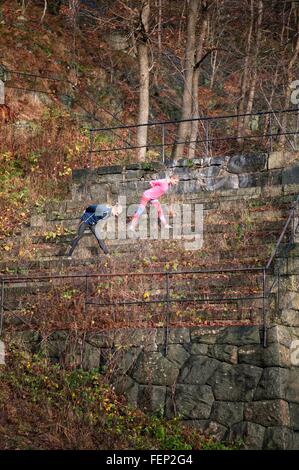 Seitenansicht des Paares machen Dehnübungen auf bewachsenen Steintreppen Stockfoto