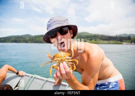 Porträt von Mitte erwachsenen Mann mit Krabben auf Fischerboot, Nehalem Bay, Oregon, USA Stockfoto