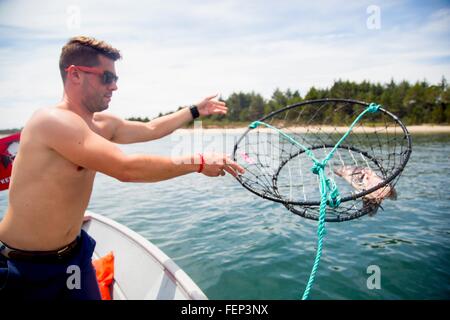 Mitte erwachsener Mann werfen Köder Krabbenfalle vom Fischerboot, Nehalem Bay, Oregon, USA Stockfoto