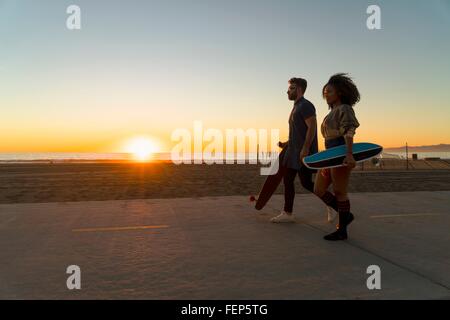 Paare, die Weg vom Strand, skateboards holding Stockfoto