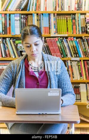 Reife Studentin mit Laptop in der Bibliothek Stockfoto