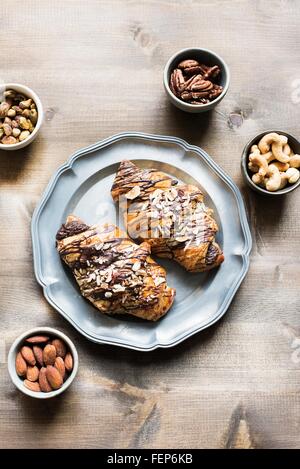 Draufsicht der Croissant auf Tablett mit Auswahl an Nüssen in Schalen Stockfoto