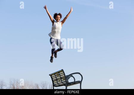 Junge Frau abspringen Parkbank Stockfoto